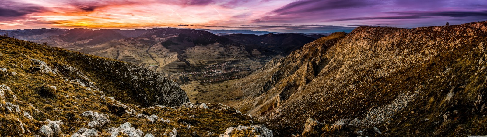 Rocky slopes of Piatra Secuiului overlooking a Transylvanian valley under a purple sunset sky
