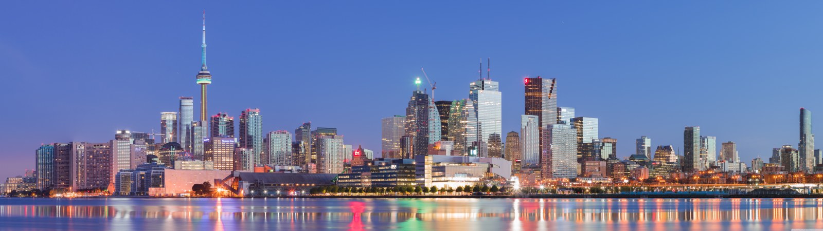 Downtown Toronto skyline and the CN Tower at dusk, city lights reflected in Lake Ontario