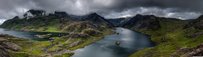 Sea loch winding between green, cloud-covered mountains on the Isle of Skye, with boats in a sheltered bay