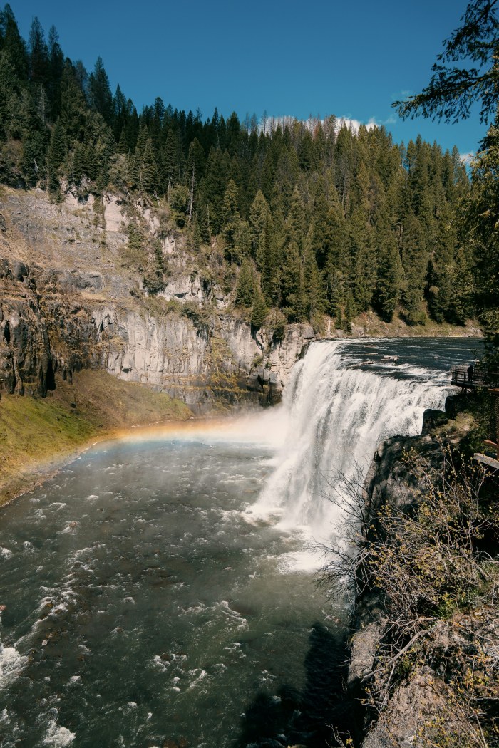 A waterfall cascades into a river with a rainbow — Waterfalls wallpaper