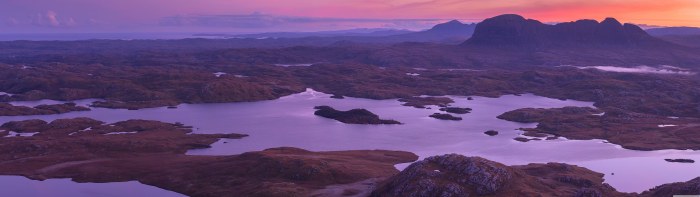 Suilven mountain rising above a maze of lochs and moorland in Assynt, Scotland, under a pink dusk sky