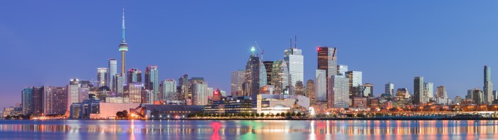 Downtown Toronto skyline and the CN Tower at dusk, city lights reflected in Lake Ontario